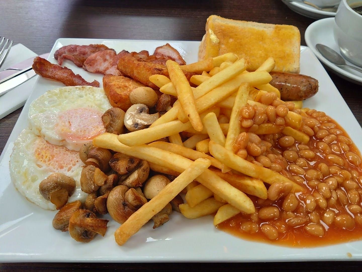 A full English breakfast: bacon, two fried eggs, sausage, mushrooms, beans, chips and toast